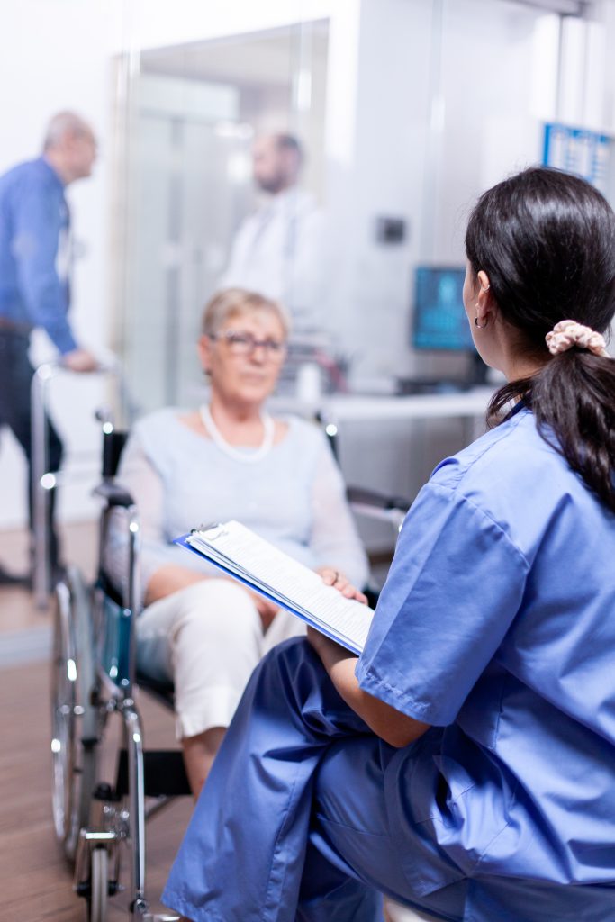 Nurse talking with handicapped senior woman in wheelchair about her disablity. Help for disabled people. Elderly assistance for old man with walking frame.